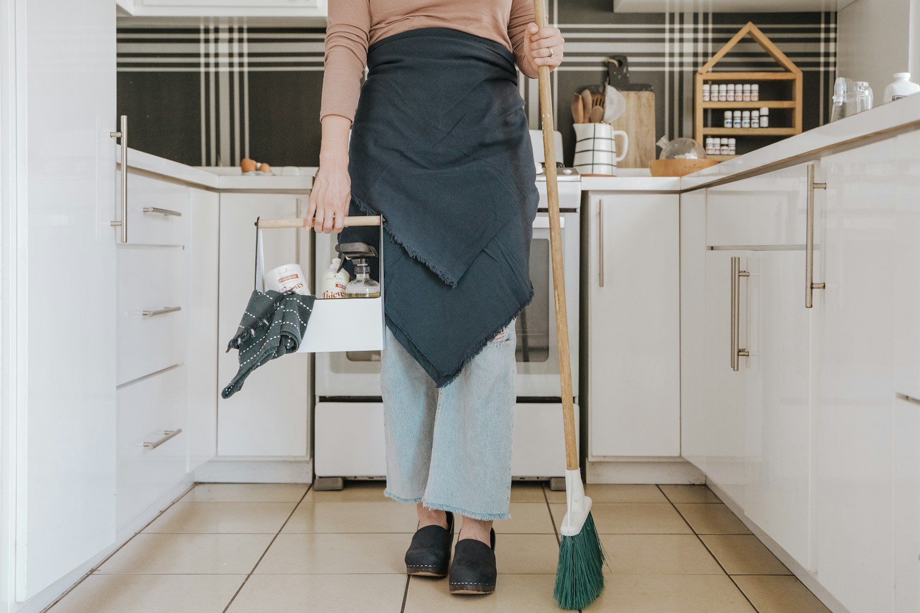 A cleaner in an apron tidying a bright kitchen